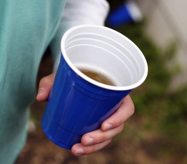Man holding alcohol cup -Alcohol Addiction Risk Factors
